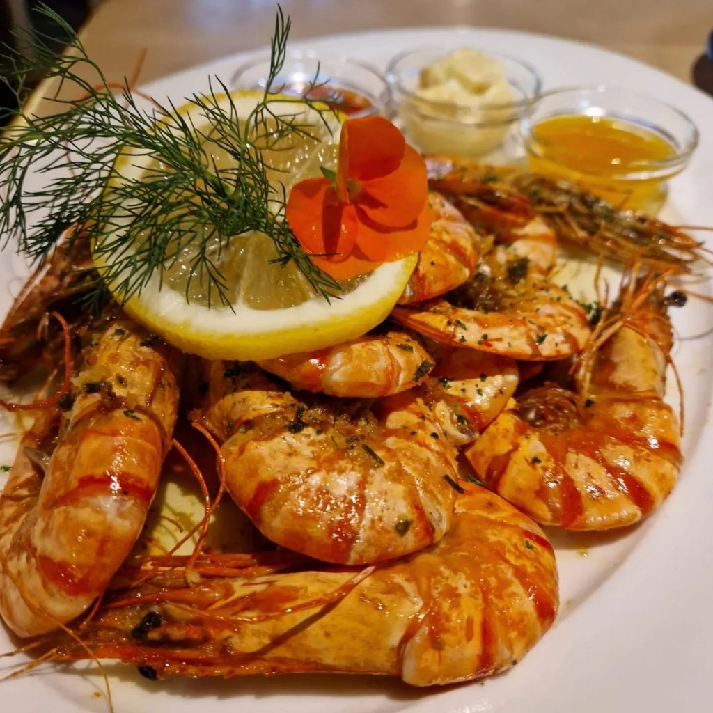 Gambas mit Zitrone, Kräutern und drei Dips auf einem Teller