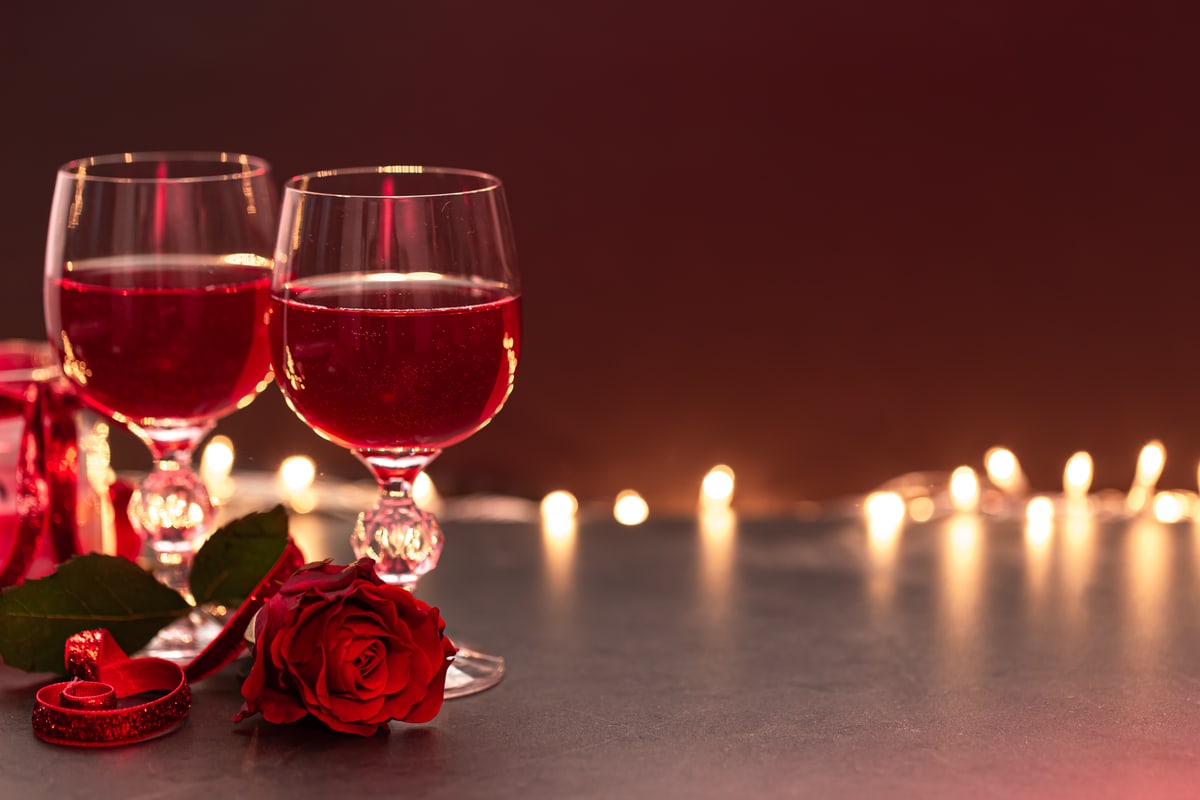 Zwei Weingläser und eine rote Rose bei Kerzenschein