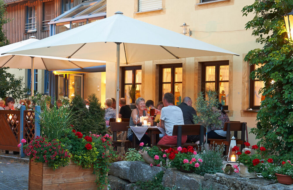 Abendstimmung im Biergarten mit Sonnenschirmen und Blumenkästen