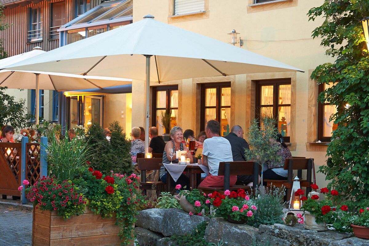 Abendstimmung im Biergarten mit Sonnenschirmen und Blumenkästen