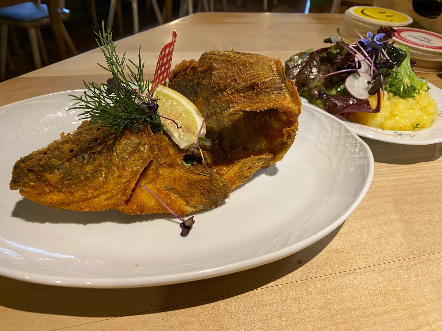 Gebackener Karpfen mit Zitrone und Kräutern, dazu Salat auf dem Holztisch im Landgasthof